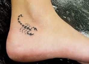Tatuagem pequena e minimalista de um escorpião feita na lateral do pé próxima ao calcanhar. 