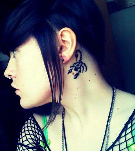 Tatuagem de escorpião feita na parte de trás da orelha de uma mulher que está de perfil. 
