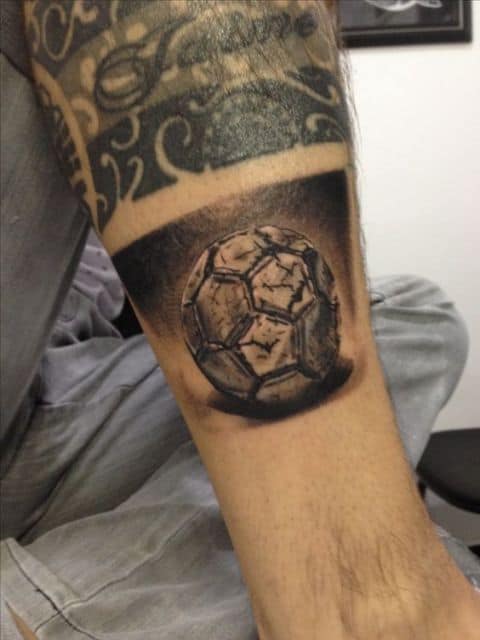 Tatuagem de uma bola de futebol desgastada.