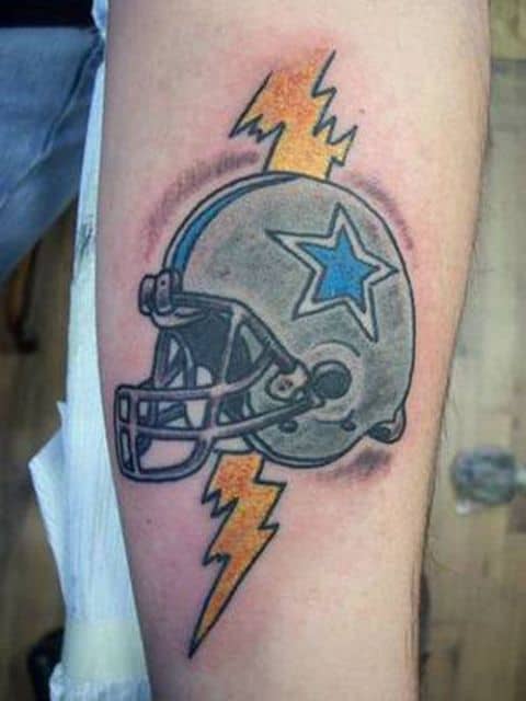 Tatuagem colorida de um capacete de futebol americano com um raio ao fundo. 