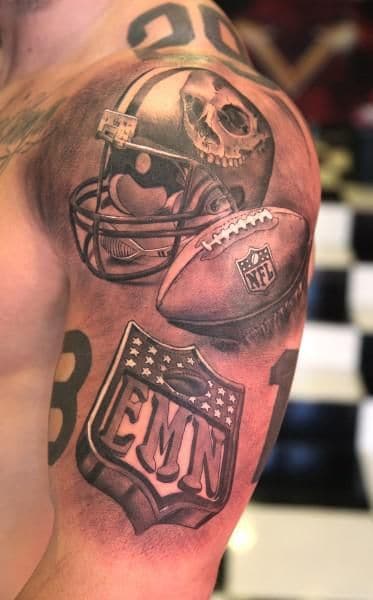 Tatuagem no braço de um capacete de futebol americano ao lado de uma bola da NFl e mais abaixo o símbolo do "EMN". 