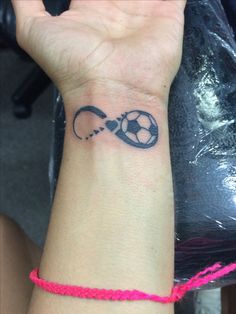 Tatuagem no pulso de um simbolo do infinito com uma bola dentro dele. 