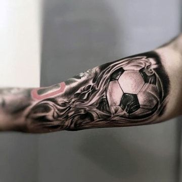 Tatuagem na parte interna do braço com uma bola e fogo saindo dela. 