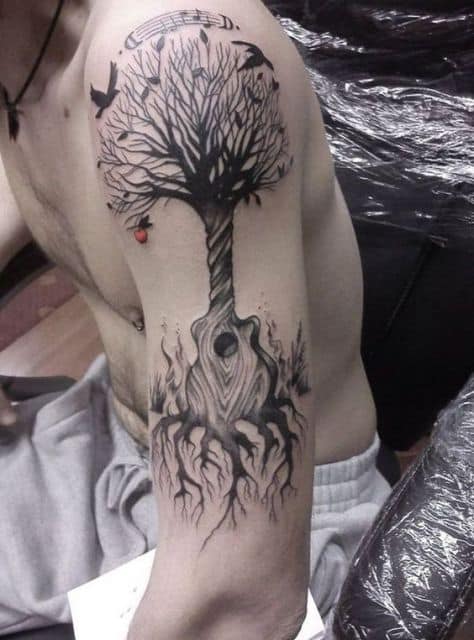 Tatuagem de uma árvore cujo tronco é formado a partir da base de um violão. 