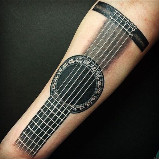 Tatuagem no antebraço com o desenho do braço de um violão. 