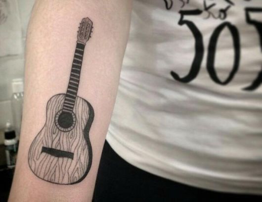 Tatuagem simples de um violão feita no braço. 