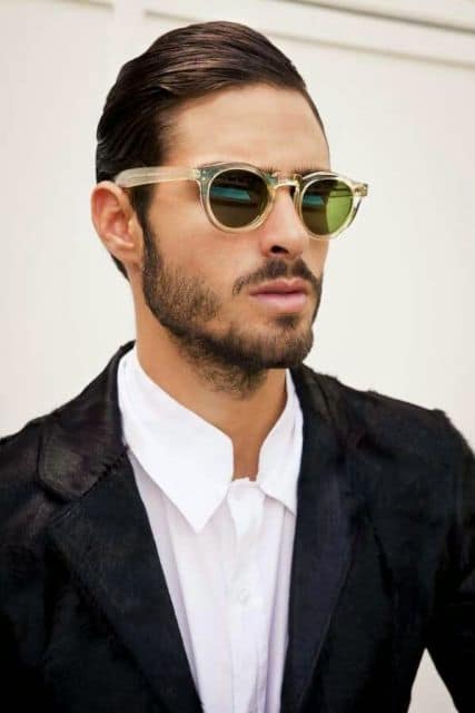 Modelo usa camisa branca, blazer preto e óculos masculino redondo.