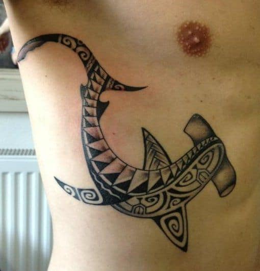 Tatuagem de um tubarão martelo maori visto de cima feita na costela. 