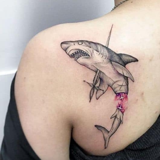 Tatuagem na lateral das costas com o desenho de um tubarão atingido por uma espada bem no coração e sua cauda se desprendendo do corpo dando origem a um corpo de sereia. 