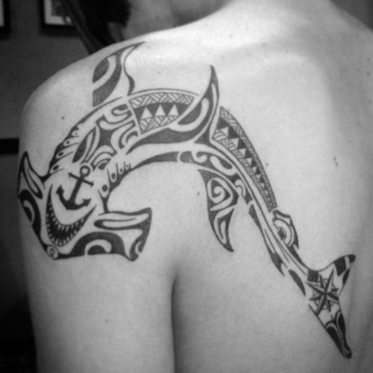 Tatuagem na lateral das costas que vai até parte do ombro com o desenho de um tubarão martelo feito no estilo maori. 