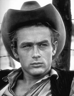 Fotografia em preto e branco de um homem com trajes típicos do cowboy americano e um chapéu country. 