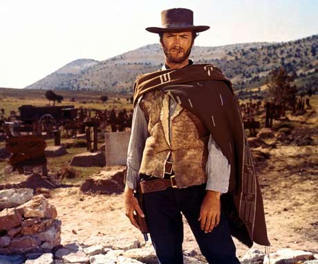 Clint Eastwood como O Homem Sem Nome vestindo um colete com um pano por cima. Ele usa um chapéu de couro desgastado. 