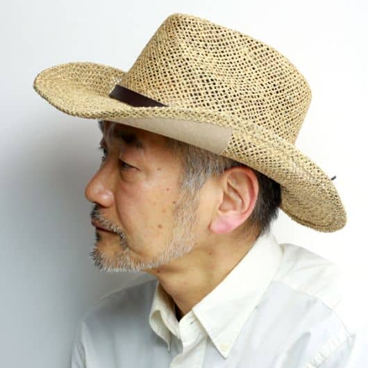 Homem idoso oriental de perfil usando um chapéu country de palha. 
