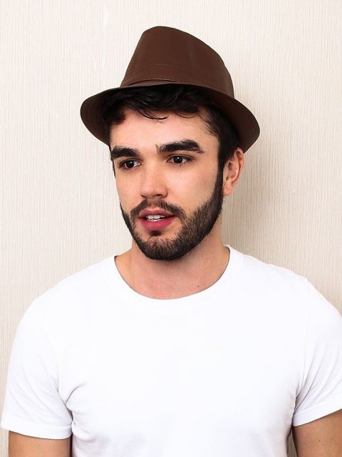 Modelo usa camiseta branca  e chapéu fedora marrom.