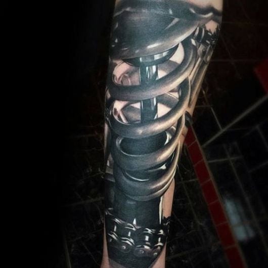 Tatuagem biomecânica com o desenho de uma mola e um amortecedor no centro dela. 