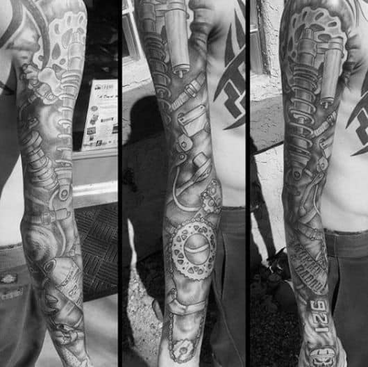 Tatuagem biomecânica fechando completamente o braço de um homem. Ela vai do ombro ao pulso e conta com elementos como engrenagens e molas. 