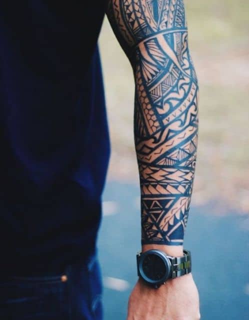 Tatuagem maori cobrindo todo o braço de um homem. 