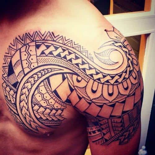 Tatuagem maori que cobre o peito e o ombro de um homem feita a partir de linhas sinuosas. 