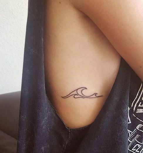 Tatuagem horizontal delicada de uma onda na costela de uma mulher.