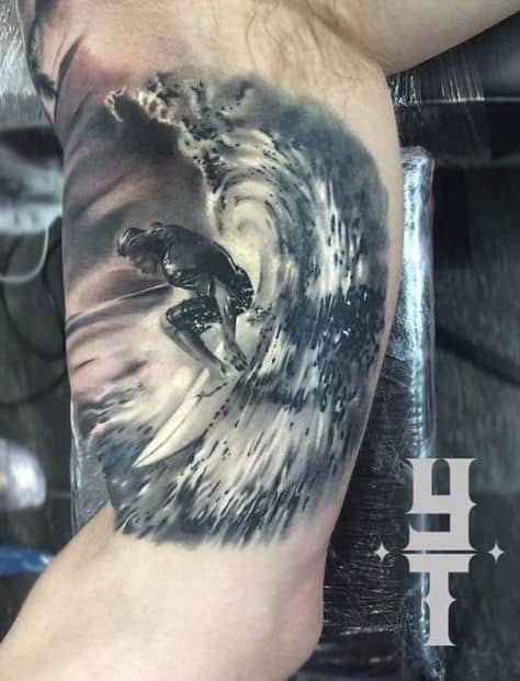 Tatuagem na parte interna do braço de um homem com o desenho de um surfista pegando uma onda alta. 