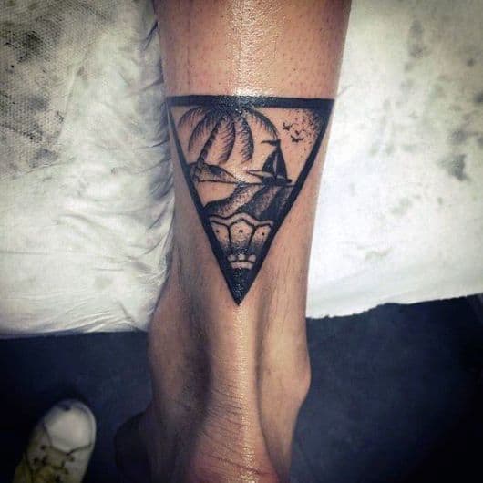 Tatuagem acima do calcanhar com um triângulo e uma paisagem de praia em seu interior. 