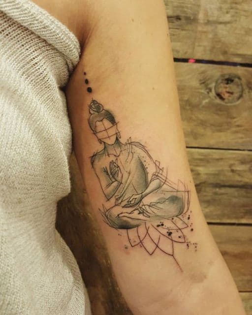 Tatuagem na parte interna do braço de uma mulher com o desenho estilo rascunho de Buda em pose de meditação.