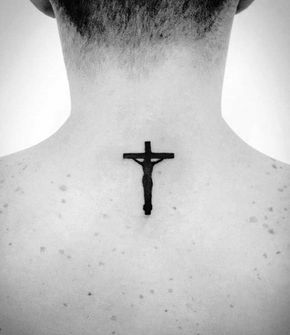 Tatuagem pequena nas costas de um homem com o desenho preenchido de preto de jesus na cruz. 