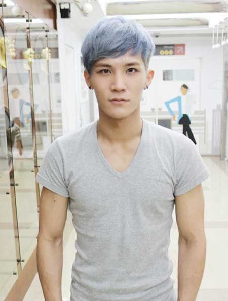 Homem asiático olhando para a câmera. Seu cabelo tem uma franja e as laterais raspadas, completamente platinado com azul.