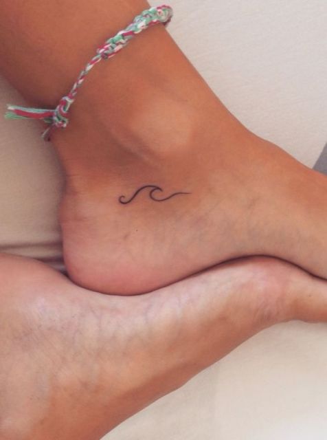 Tatuagem no calcanhar com o desenho de uma onda pequena formada por uma linha delicada. 