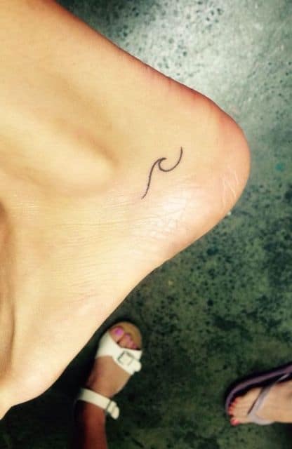 Tatuagem no calcanhar muito pequena com o desenho de uma linha formando uma onda. 