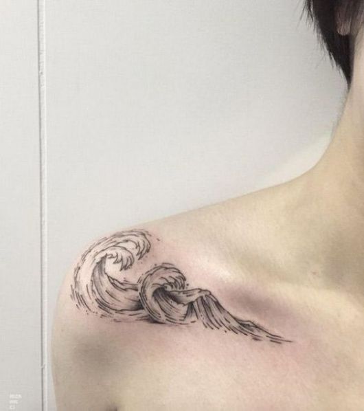 Tatuagem na parte frontal do ombro com o desenho de duas ondas se formando no meio do mar. 