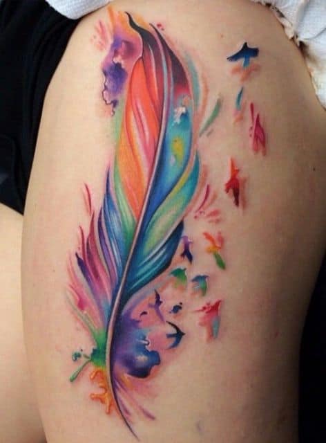 Tatuagem de pena aquarela nas cores azul, laranja, verde e rosa.