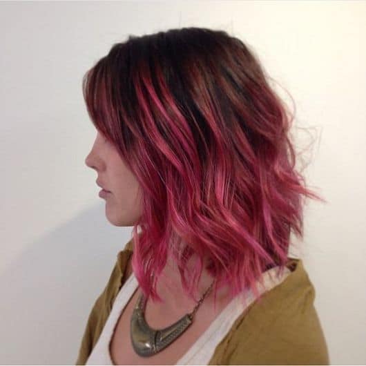 Mulher de perfil, com cabelo com Ombré Hair e mechas rosas.