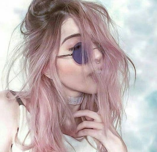 Mulher com cabelo curto com ombré hair rosa e óculos.