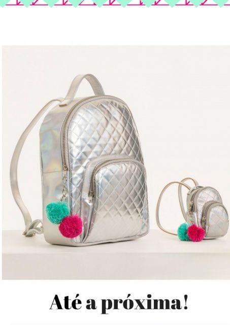 Ilustração com mochila holográfica prata com chaveiros nas cores verde e rosa.