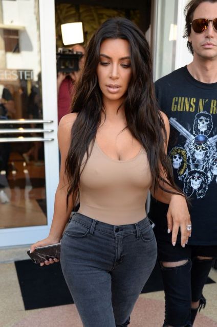 Kim Kardashian com calça jeans e blusa bege.