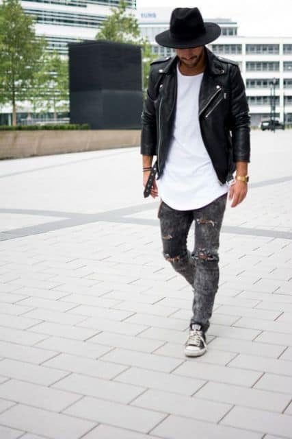 Chapéu preto masculino no look rocker, combinando com a calça destroyed, o tênis All Star, a camisa oversized branca e a jaqueta de couro