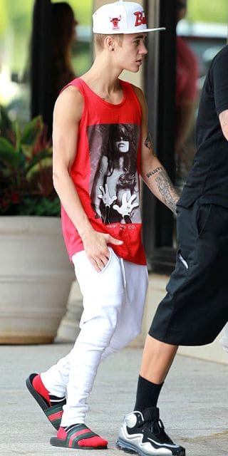 Justin Bieber usando slide preto com meia vermelha