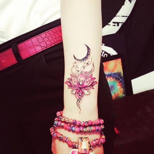 modelo com tatuagem de mandala flor de lótus cor de rosa no pulso.