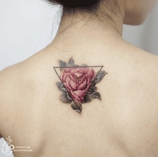 tatuagem flor de lótus dentro de um triangulo nas cores rosa e verde escuro.