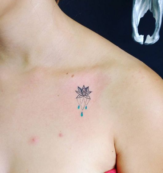 tatuagem flor de lótus pequena com detalhes na cor azul.