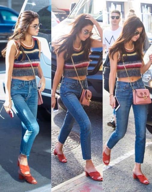Selena Gomez com bolsa rosa, jeans e cropped.