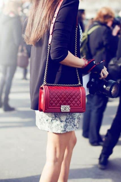 Bolsa vermelha combinada com saia estampada branca e blazer preto.