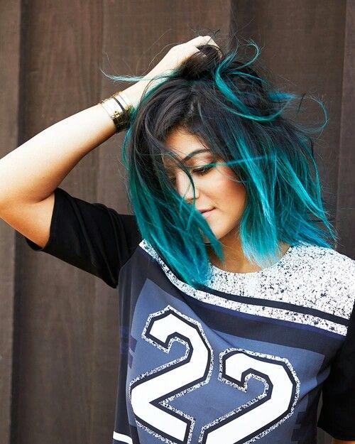 Mulher com cabelo preto e californiana azul turquesa.
