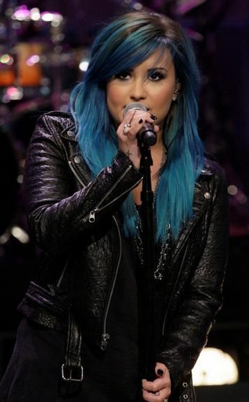Demi Lovato cantando com cabelo azul.