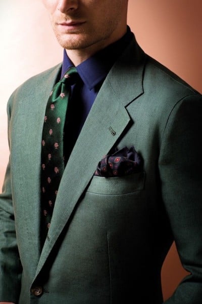 Um lindo terno verde escuro com gravata estampada e um lenço escuro