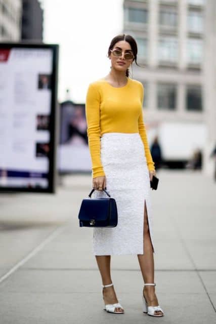 Mulher com saia lápis branca e blusa mostarda.