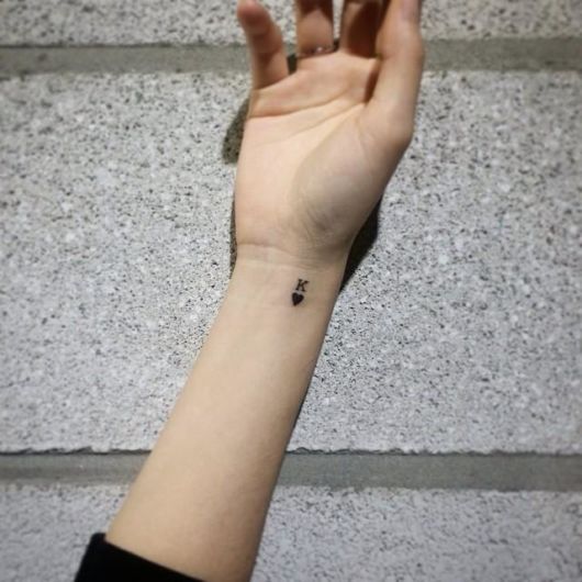 tatuagem pequena no pulso com a letra K e um coração.
