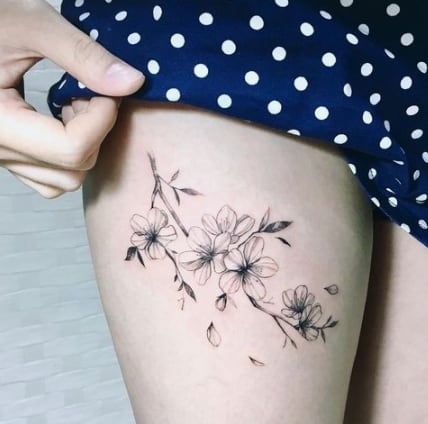 tattoo de flor de cerejeira na perna