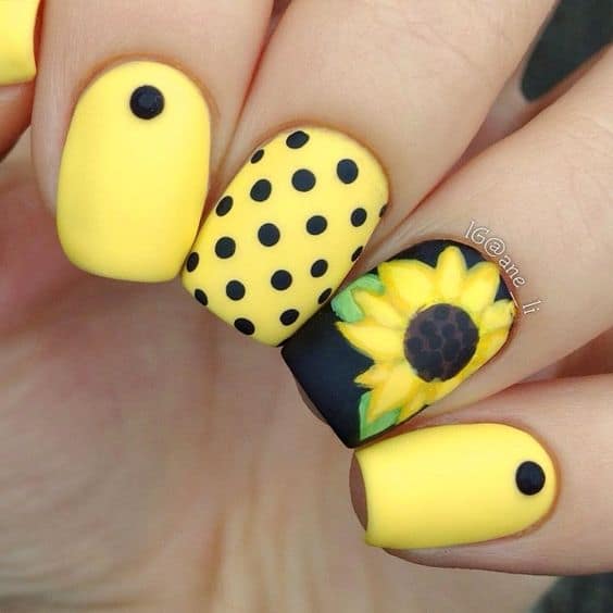 unhas com esmalte amarelo e nail art preta